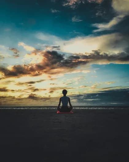 A beach at sunset before and after the person sitting on the sand is erased